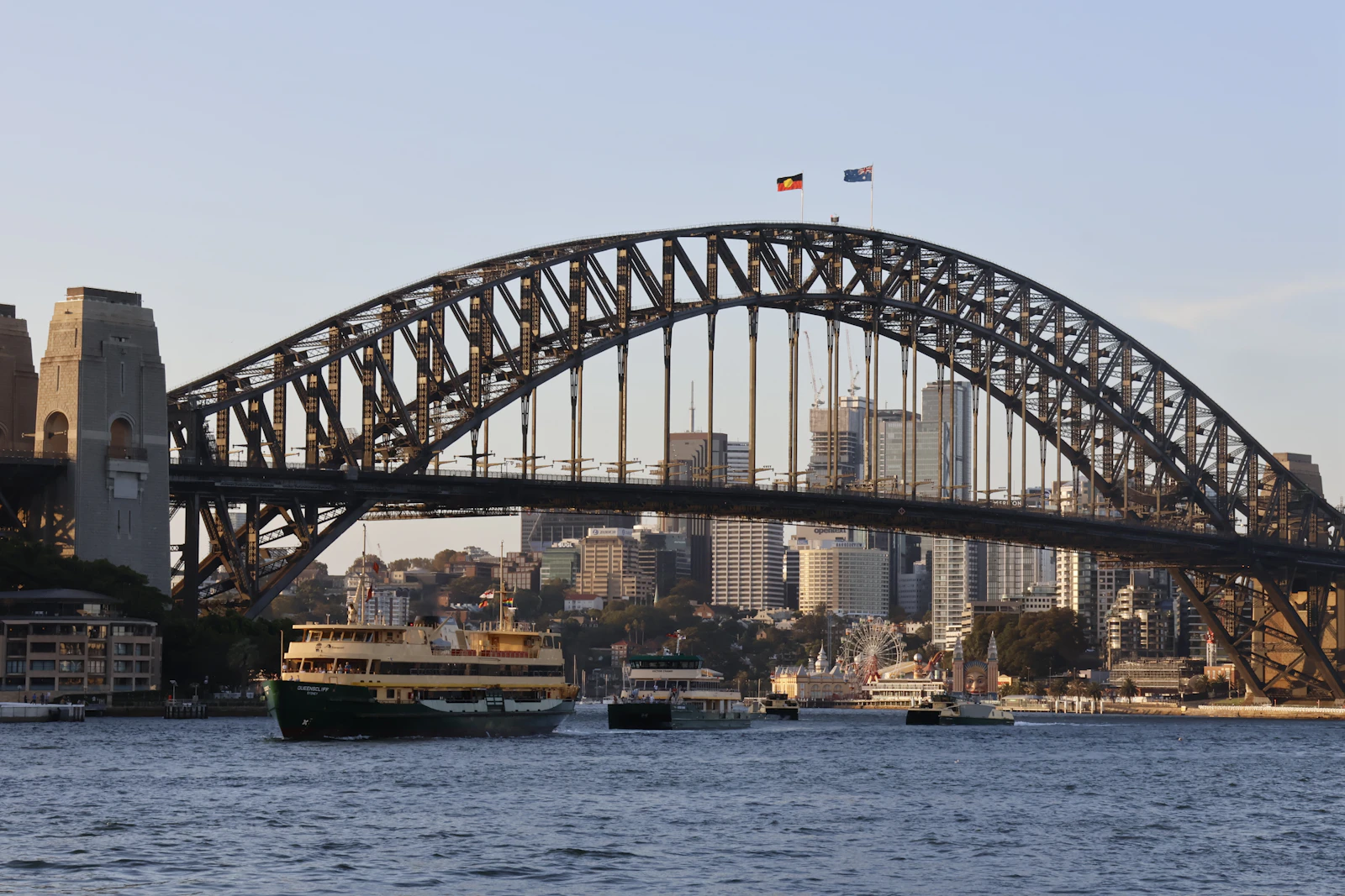 Sydney Harbour Bridge with a ferry crossing in front of the city skyline